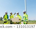 Team of professional electrical engineers in fully safety suit are working and discussing together at the windmill electric generating turbine. Electricians working at the site of windmill turbine. 131013197
