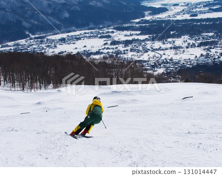 Hakuba Iwatake Snowfield - Skiers skiing down Sunny Valley with Hakuba Village in the background 131014447