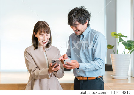 Businesswoman and businessman looking at smartphone in office (IT company employee) 131014812