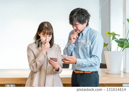 Businessman and businesswoman talking while looking at smartphone (worried, troubled, stressed, trouble) 131014814