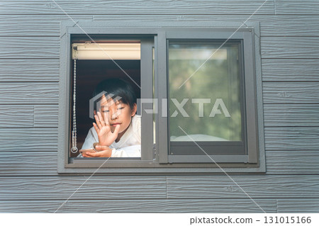 一名小學生在屋內用智慧型手機向朋友揮手致意 131015166