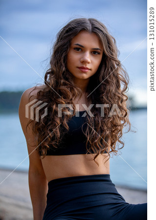 A Young Woman Posing at the Beach Against a Beautiful Sunset Sky, Capturing the Moment A Young Woman Posing at the Beach Against a Beautiful Sunset Sky, Capturing the Moment 131015289