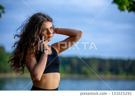 A young woman is enjoying the beauty of nature while talking on her phone happily today 131015291