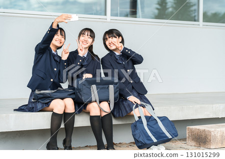 Junior high and high school girls taking selfies with their smartphones in the school hallway (after school, going home, friends) 131015299