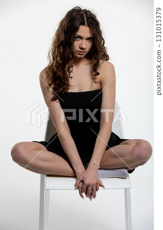 A Fashion Pose Featuring a Stylish Model Elegantly Sitting on a Chair in a Studio Environment A Fashion Pose Featuring a Stylish Model Elegantly Sitting on a Chair in a Studio Environment 131015379