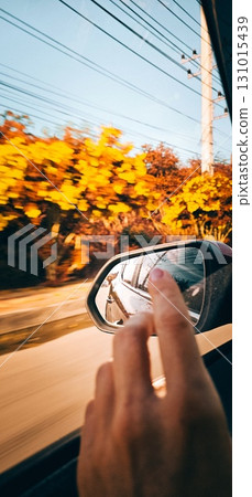 A hand reaches out towards the blurred view of autumn from a moving car. A hand reaches out towards the blurred view of autumn from a moving car. 131015439