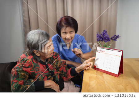Asian Elderly Woman with Dementia Practicing Read Calendar. 131015532