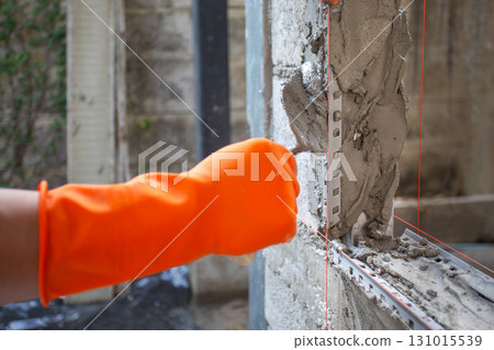 Construction worker using a pvc corner bead to plaster a window corner. 131015539
