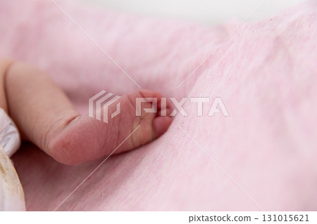 An Adorable and Cute Baby Foot Resting Comfortably on a Soft and Gentle Pink Fabric Background 131015621