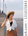 Stylish woman in straw hat posing outdoors at sunset. 131015843