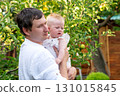 Father cradles curious baby beside apple tree branches 131015845