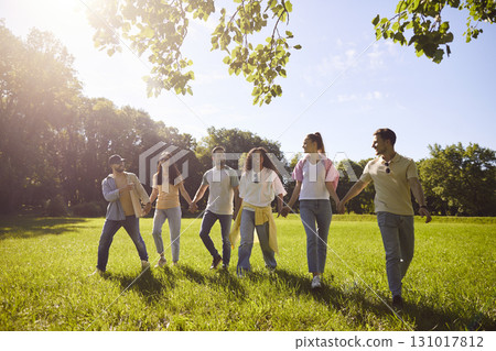 Happy diverse group of friends, young people walking side by side across grassy field, green park Happy diverse group of friends, young people walking side by side across grassy field, green park 131017812