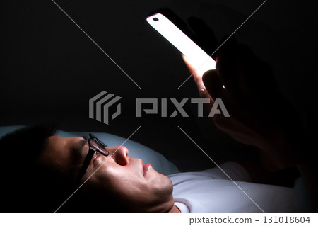 一名男子躺在床上操作智慧型手機 131018604