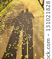 The shadows of two people reflected on the path covered with fallen leaves 131021828