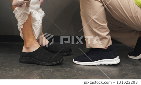 Asian caregiver changing elderly person's diaper 131022298