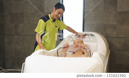 Elderly Asian people receiving assistance with bathing using a machine 131022302