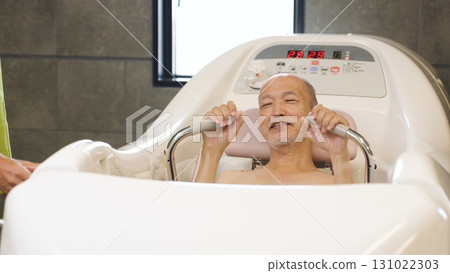Elderly Asian people receiving assistance with bathing using a machine Elderly Asian people receiving assistance with bathing using a machine 131022303