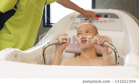 Elderly Asian people receiving assistance with bathing using a machine Elderly Asian people receiving assistance with bathing using a machine 131022304