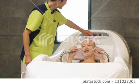 Elderly Asian people receiving assistance with bathing using a machine 131022305