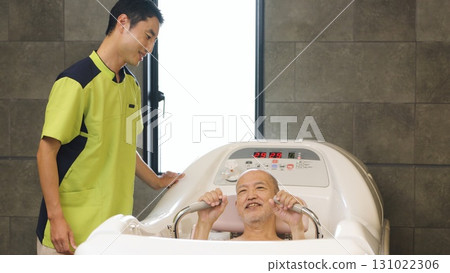 Elderly Asian people receiving assistance with bathing using a machine 131022306