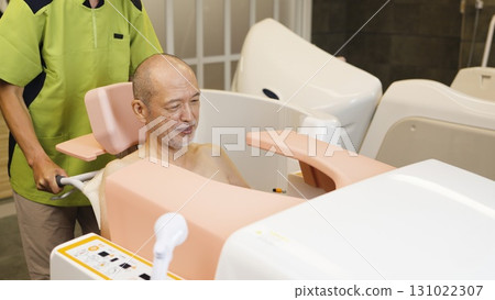 Elderly Asian people receiving assistance with bathing using a machine Elderly Asian people receiving assistance with bathing using a machine 131022307