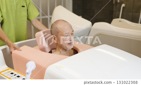 Elderly Asian people receiving assistance with bathing using a machine Elderly Asian people receiving assistance with bathing using a machine 131022308
