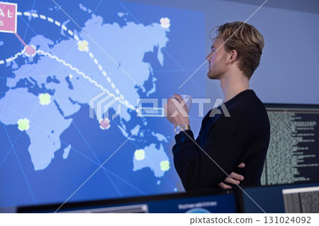 Cybersecurity analyst monitoring a world map on a digital display 131024092