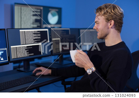 Young male cybersecurity analyst monitoring network data and threat intelligence dashboards 131024093