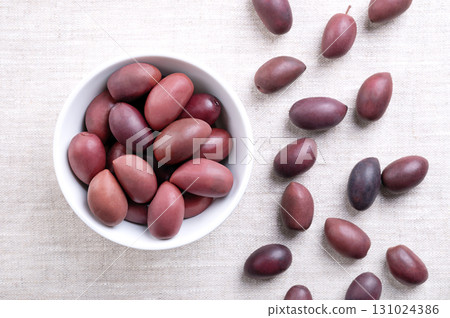 Kalamata olives with pit, in white bowl on linen. Hand-picked large, purple olives, with smooth, meaty texture, named after Greek city Kalamata. Preserved in wine vinegar. Also called Kalamon olives. Kalamata olives with pit, in white bowl on linen. Hand-picked large, purple olives, with smooth, meaty texture, named after Greek city Kalamata. Preserved in wine vinegar. Also called Kalamon olives. 131024386