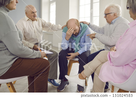 Group of friendly seniors people supporting elderly man on a therapy session sitting in a circle. 131024583