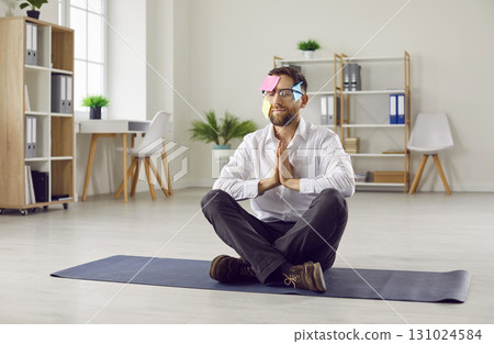 Funny relaxed business man meditating in office or at home sitting on the floor on yoga mat. Funny relaxed business man meditating in office or at home sitting on the floor on yoga mat. 131024584