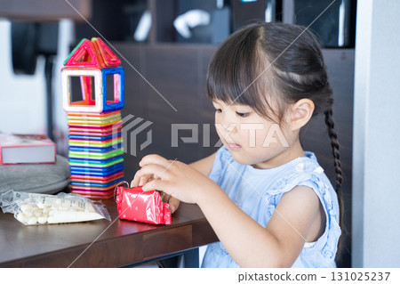 A girl opening a biscuit and playing with building blocks A girl opening a biscuit and playing with building blocks 131025237