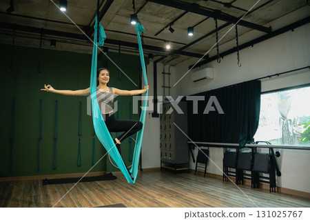 Young woman slim body fitness girl practicing fly yoga in the gym Young woman slim body fitness girl practicing fly yoga in the gym 131025767