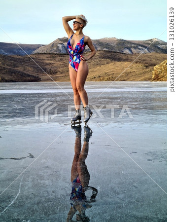 A brave woman in a swimsuit poses on the clear ice, enjoying the chilly mountain air. 131026139
