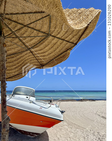 Relaxing day by the blue sea in Djerba, Tunisia with a boat under a straw parasol 131026200