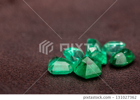 A pile of green gemstones on a dark surface A pile of green gemstones on a dark surface 131027362
