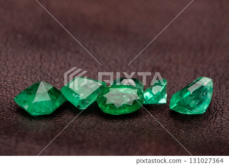 A pile of green gemstones on a dark surface A pile of green gemstones on a dark surface 131027364