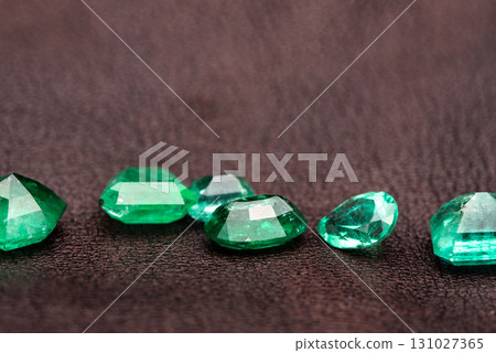 A row of green gemstones are laid out on a dark surface A row of green gemstones are laid out on a dark surface 131027365
