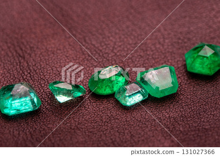 A collection of green gemstones are displayed on a brown surface A collection of green gemstones are displayed on a brown surface 131027366
