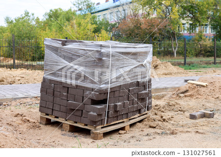 Pallet of Paving Stones Covered with Plastic Wrap to Protect from Rain, Showcasing Construction Materials Ready for Outdoor Use Pallet of Paving Stones Covered with Plastic Wrap to Protect from Rain, Showcasing Construction Materials Ready for Outdoor Use 131027561