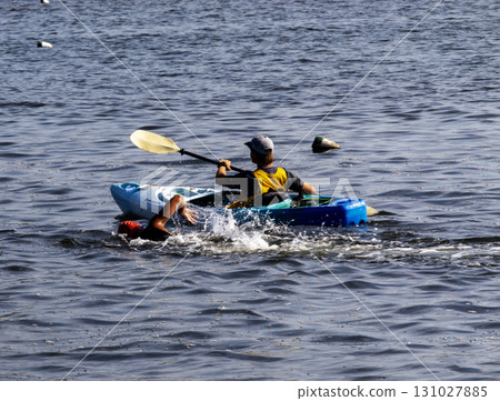 Kayaker Paddling Alongside Swimmer in the Calm Waters of The Great South Bay off the Coast of Long Island Kayaker Paddling Alongside Swimmer in the Calm Waters of The Great South Bay off the Coast of Long Island 131027885