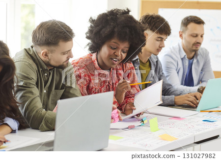 Young office diverse colleagues sitting in boardroom at desk with laptop to brainstorm, discuss 131027982