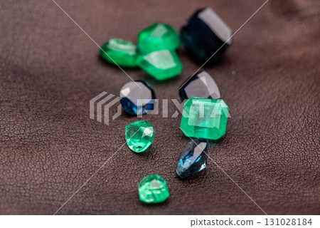 A pile of gemstones, including green and blue, are on a brown surface A pile of gemstones, including green and blue, are on a brown surface 131028184