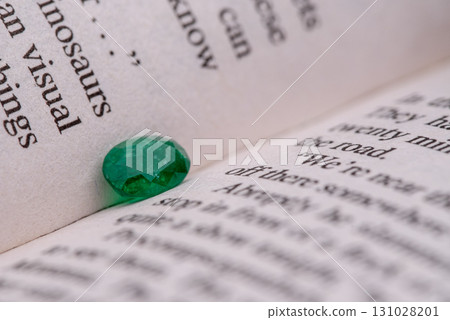 A green gemstone is on a page of a book A green gemstone is on a page of a book 131028201