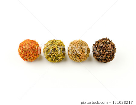 Four different colored balls with nuts and spices on top 131028217
