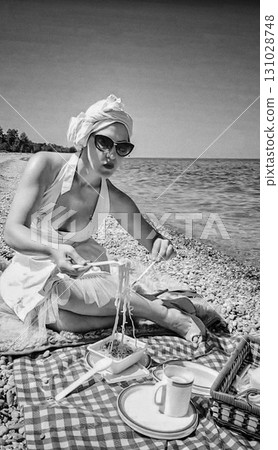 A woman enjoys a seaside picnic, eating spaghetti on a checkered blanket in a vintage style. 131028748