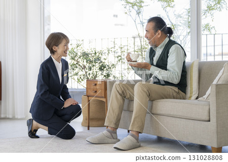 A middle-aged female facility staff member talking to a senior man 131028808