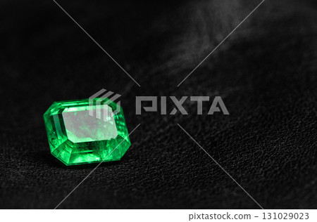 A green gemstone sits on a black surface 131029023