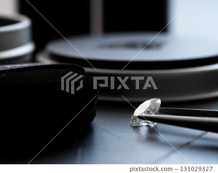 A diamond is on a table next to a magnifying glass 131029327