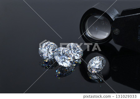 Three diamonds are on a table next to a magnifying glass Three diamonds are on a table next to a magnifying glass 131029333